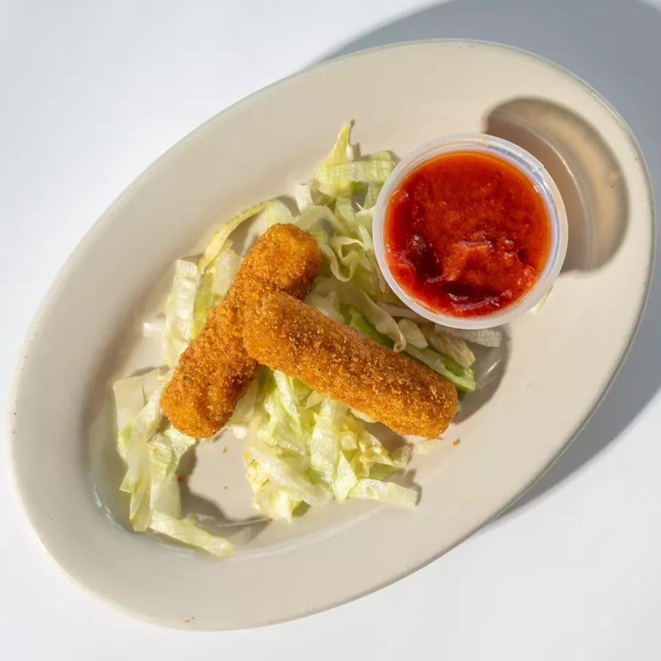 Two golden-brown mozzarella sticks on a bed of shredded lettuce with a side of red marinara sauce.